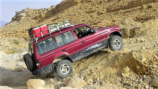 רכב שטח אדום מטפס על שביל סלעי תלול בטיול ג'יפים בישראל